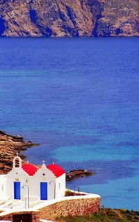 A pretty church with red roof and blue doors by the beach in Mykonos